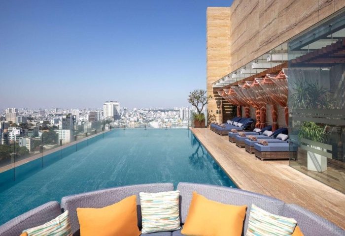 Hotel Des Arts Saigon rooftop pool, a best gay hotel. Infinity pool overlooking the city. Loungers and seating area. Gay travel.