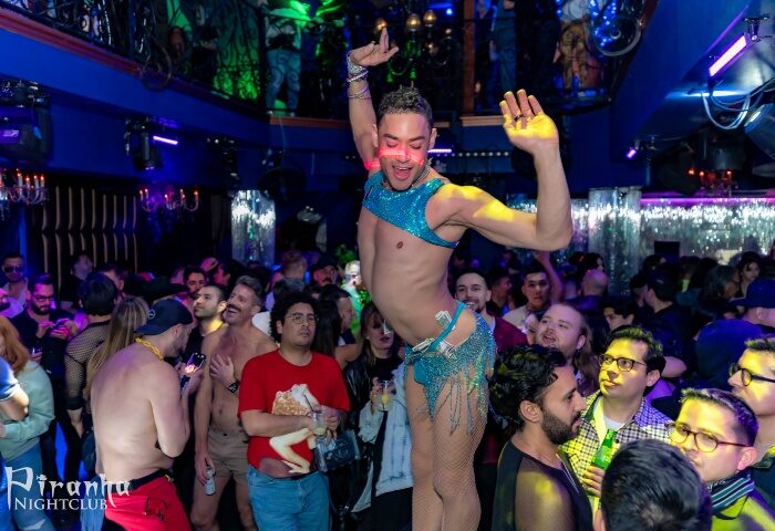 Gay Las Vegas: Dancer at Piranha Nightclub, a popular gay bar. The club is crowded, with blue lighting and shirtless patrons.