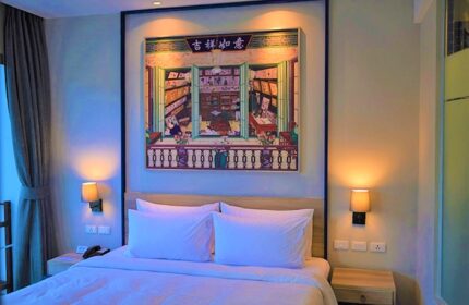Holiday Inn Express Krabi Ao Nang Beach hotel room. Bed with white linens, painting of a library. Best gay location in Krabi for travelers.