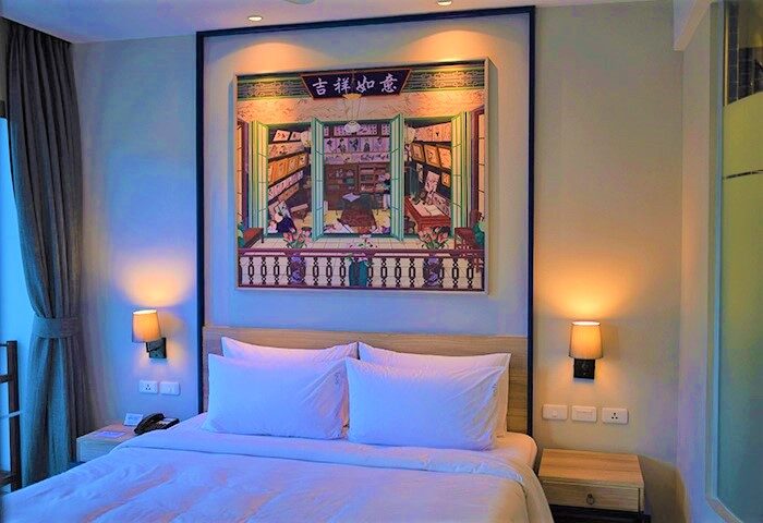 Holiday Inn Express Krabi Ao Nang Beach hotel room. Bed with white linens, painting of a library. Best gay location in Krabi for travelers.