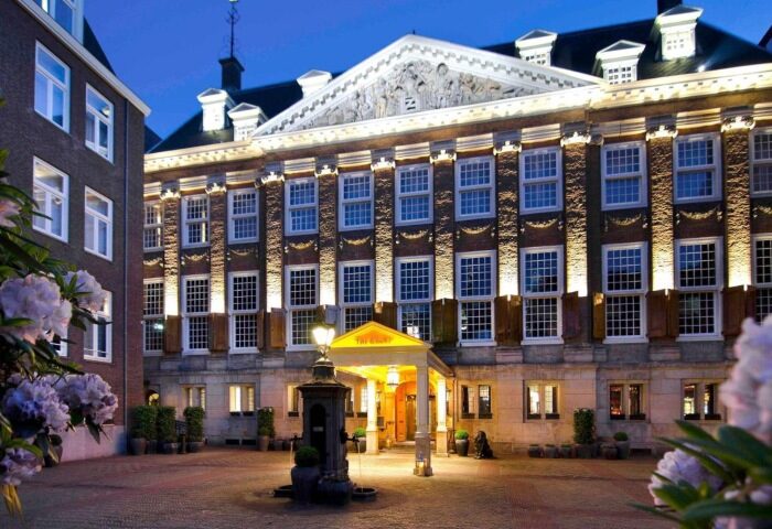 Sofitel Legend The Grand Amsterdam, a best gay luxury hotel on Amsterdam Canal. Exterior view at dusk, showcasing architecture and entrance.