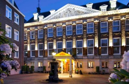Sofitel Legend The Grand Amsterdam, a best gay luxury hotel on Amsterdam Canal. Exterior view at dusk, showcasing architecture and entrance.
