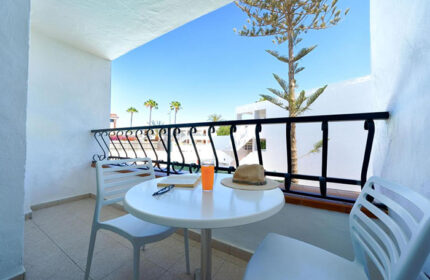 Atlantic Sun Beach gay men only hotel balcony view. Table with drink, hat, book. Best for solo gay travelers in Gran Canaria.