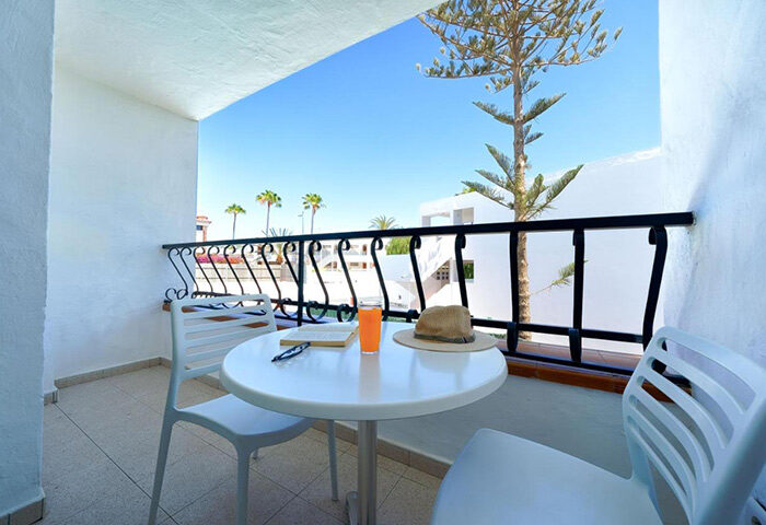 Atlantic Sun Beach gay men only hotel balcony view. Table with drink, hat, book. Best for solo gay travelers in Gran Canaria.