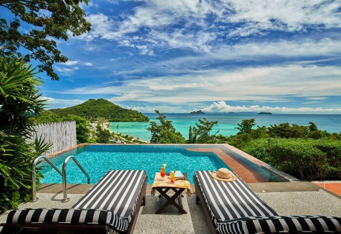 SAii Phi Phi Island Village beachfront hotel pool view for gay travelers. Tropical drinks, lounge chairs, turquoise sea, idyllic gay vacation.