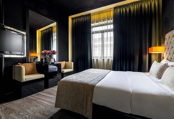 Gay Lisbon honeymoon hotel idea: 9Hotel Mercy room. Dark decor, plush bed, chairs, and desk. Luxury stay in Lisbon's gayborhood.