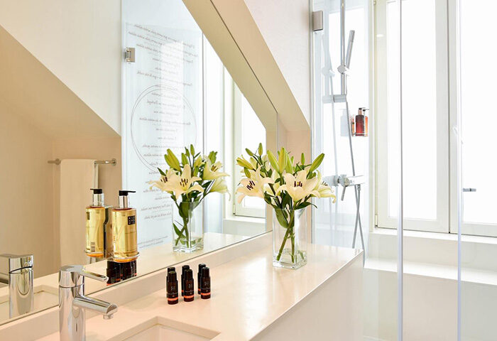 My Story Hotel Ouro bathroom. Honeymoon hotel idea in Lisbon's tourist area. Sink, mirror, flowers, and shower.