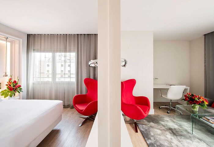 NH Collection Barcelona Gran Hotel Calderon room. Luxury gay hotel idea in Barcelona's gayborhood. Red chairs, bed, desk.