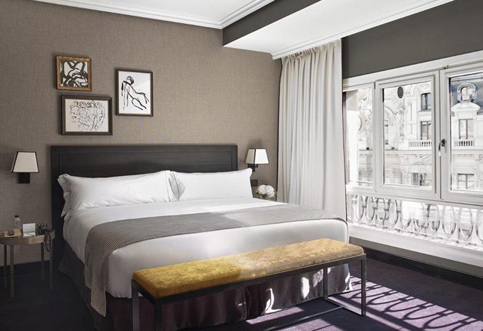 The Principal Madrid Hotel room, best honeymoon luxury hotel idea for gay couples. King bed, bench, city view, stylish art.