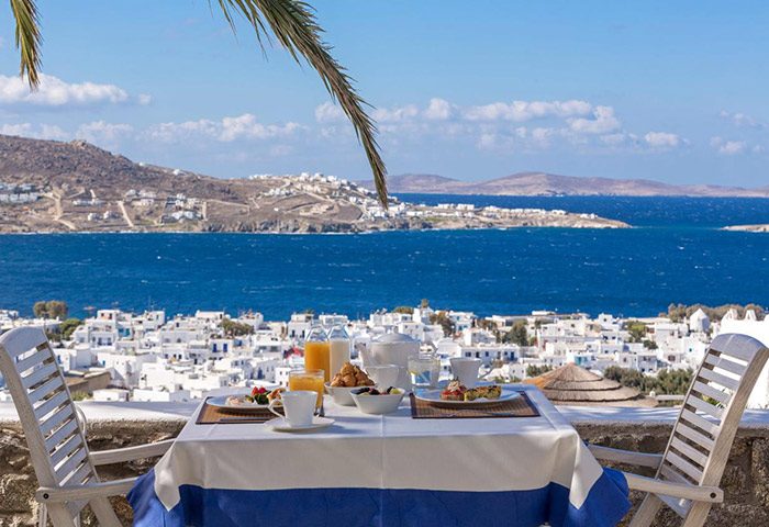 Breakfast at Vencia Boutique Hotel, a gay-friendly hotel in Mykonos Town. Sea view, white buildings, blue accents. Best hotel breakfast.
