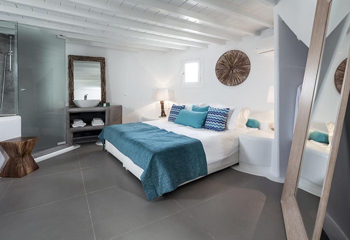 Absolute Mykonos Suites: Instagrammable gay hotel room. Modern design, blue accents, white walls, and sleek bathroom. Ideal for gay travel.