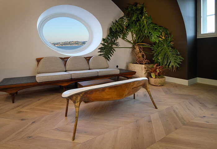 Bairro Alto Hotel's luxury interior. View from a Lisbon gayborhood hotel room with a round window, modern furniture, and a leafy plant.