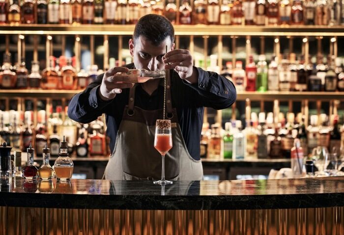 Bartender mixes cocktail at Academias Hotel, Athens. Luxury gay hotel near Alexander Sauna. Best gay travel advice for gay men.