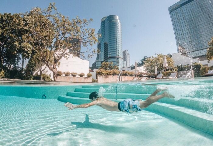 Gay man swims in Grand Hyatt Erawan Bangkok's pool. Luxury hotel in Bangkok city center. Best gay hotels for gay travelers.
