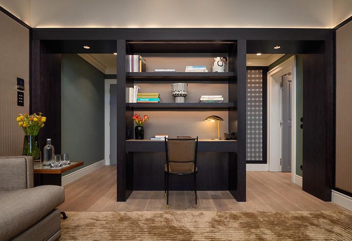 Bairro Alto Hotel's luxury living room in Lisbon's gayborhood. Desk with shelves, chair, flowers, and stylish design. Gay travel inspiration.