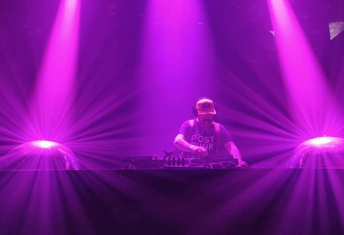 DJ at BRÜT London, a gay dance club. Purple lights shine on the DJ and disco balls. Best monthly gay dance club in London for gay men.