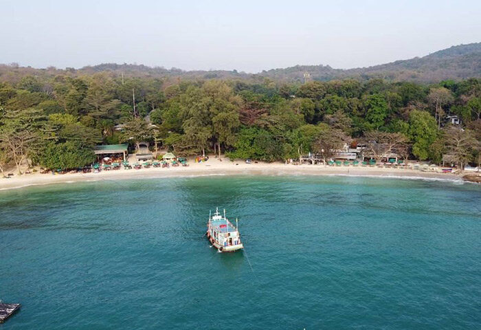 Beachfront view of Tubtim Resort, Koh Samet, a popular gay-friendly hotel. Turquoise water, white sand, and lush greenery create a tropical paradise.