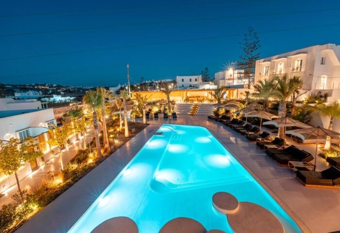 Akkadian Gay Only Hotel Mykonos pool view at night. Best party gay hotel with illuminated pool and sunbeds. Gay travel advice.