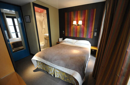 Hotel Du Vieux Saule bedroom in Paris' gayborhood Marais. Room with double bed, colorful headboard, and bathroom. Best party hotel for gay men.