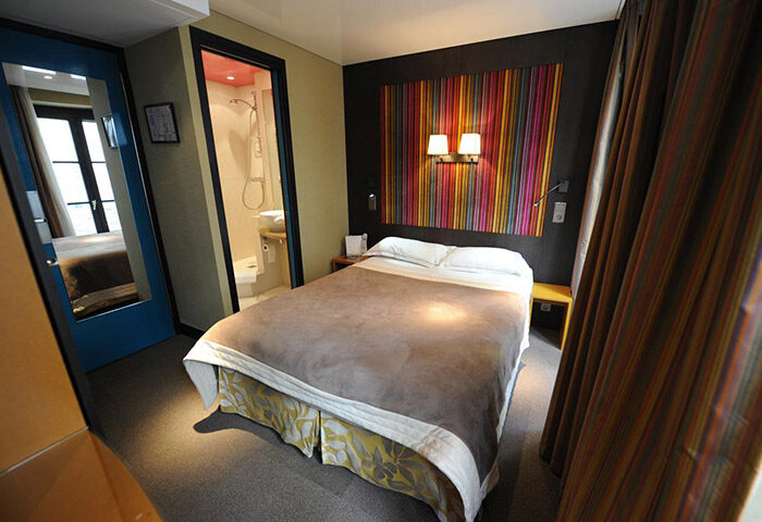 Hotel Du Vieux Saule bedroom in Paris' gayborhood Marais. Room with double bed, colorful headboard, and bathroom. Best party hotel for gay men.