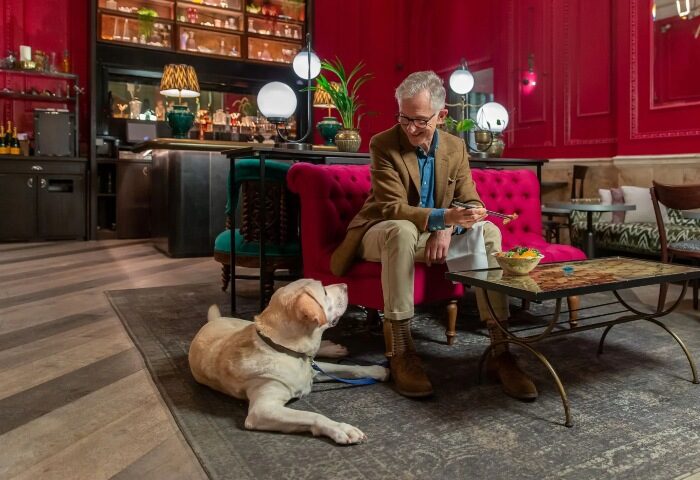 Andaz London Liverpool Street, a pet-friendly hotel. Gay man with his dog in Shoreditch hotel lounge. Best hotels for gay travel.