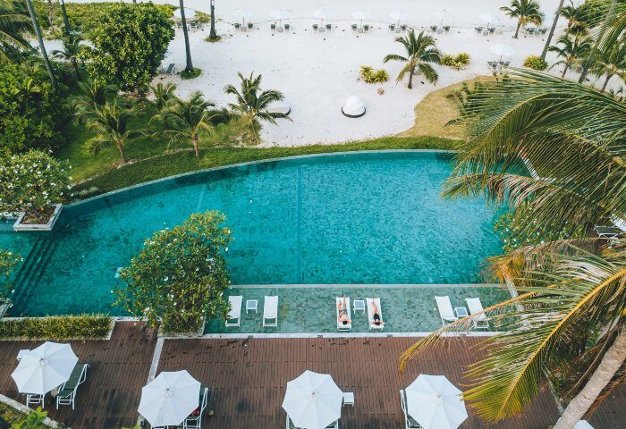 SAii Phi Phi Island Village's private beach and pool. Gay resort with palm trees, white sand, and turquoise water. Perfect for gay travel.