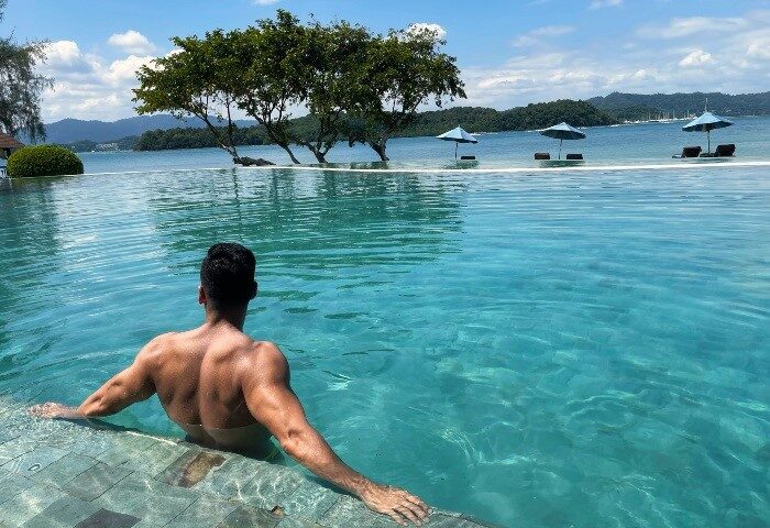 Man in infinity pool at The Naka Island, a Luxury Collection Resort & Spa, Phuket. Best private pool villas beachfront gay hotels Phuket.