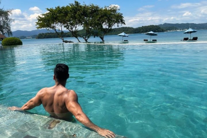 Man in infinity pool at The Naka Island, a Luxury Collection Resort & Spa, Phuket. Best private pool villas beachfront gay hotels Phuket.