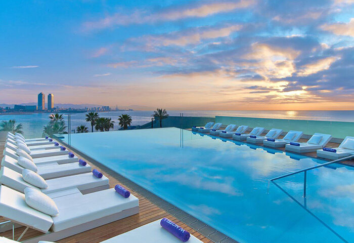 W Barcelona hotel rooftop pool. Best hotel for gay travelers. Skyline view with lounge chairs. Gay travel advice.