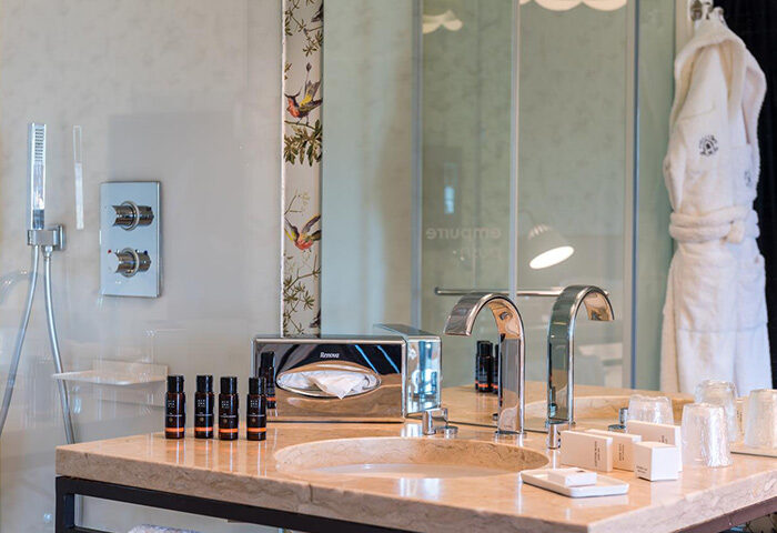 Lisboa Carmo Hotel's upscale bathroom. Marble vanity with dual sinks, designer toiletries, and plush robe. Best gay hotel in Lisbon update.