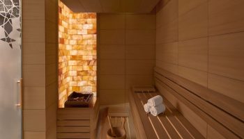 JW Marriott Hotel Istanbul Marmara Sea's luxury sauna. Wellness hotel near gay hamams. Salt wall, wooden benches, towels, and bucket.