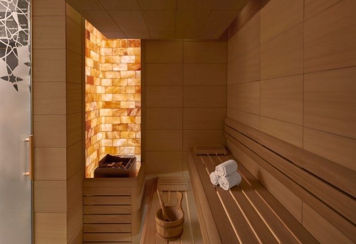 JW Marriott Hotel Istanbul Marmara Sea's luxury sauna. Wellness hotel near gay hamams. Salt wall, wooden benches, towels, and bucket.