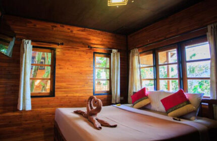 The Cobble Beach Hotel room. Gay honeymoon beachfront hotel in Ton Sai, Phi Phi. Wooden walls, bed with swan towels, red pillows.