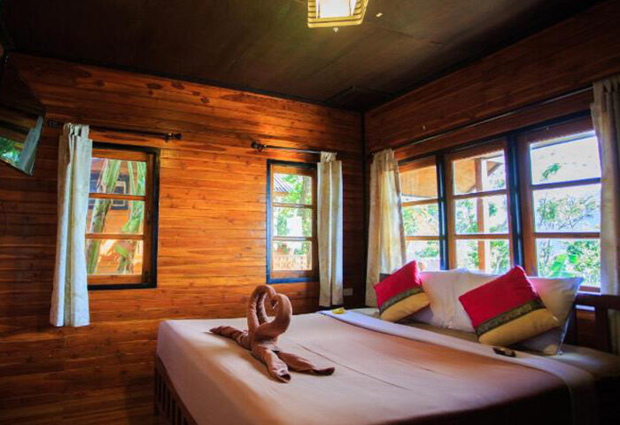 The Cobble Beach Hotel room. Gay honeymoon beachfront hotel in Ton Sai, Phi Phi. Wooden walls, bed with swan towels, red pillows.