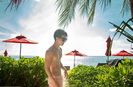 Gay resort Anantara Rasananda Koh Phangan Villas: Man on beach, red umbrellas, blue sea. Best choice for gay travel in Koh Phangan.