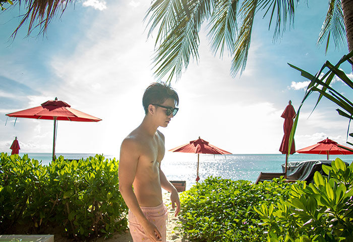 Gay resort Anantara Rasananda Koh Phangan Villas: Man on beach, red umbrellas, blue sea. Best choice for gay travel in Koh Phangan.
