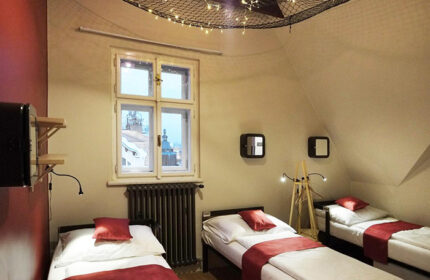 Czech Inn, a gay-friendly hostel in Prague's Vinohrady. Room with three beds, red accents, and a view of the city. Best for gay travelers.