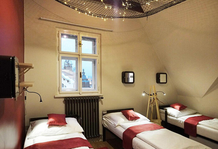 Czech Inn, a gay-friendly hostel in Prague's Vinohrady. Room with three beds, red accents, and a view of the city. Best for gay travelers.