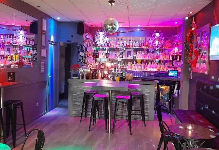 Interior of Betty Boo's gay bar in Benidorm, Spain. Disco ball, bar stools, and shelves of liquor bottles under colorful lighting.
