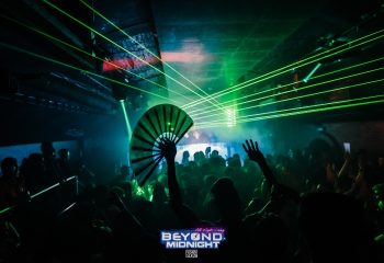 Beyond Club, London's gay dance club in Vauxhall. Crowd partying under green laser lights, one person holding a fan. Fire London.