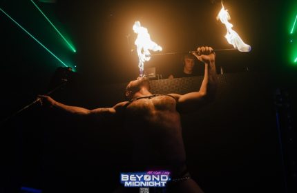 Fire London's Beyond Club gay party: shirtless man, leather harness, fire breather. Nightlife at London's hottest gay party. Dark room vibe.
