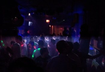 Crowded gay bar in Chicago. People dancing under blue & green lights. Big Chicks is a popular LGBTQ+ venue for gay men's travel.