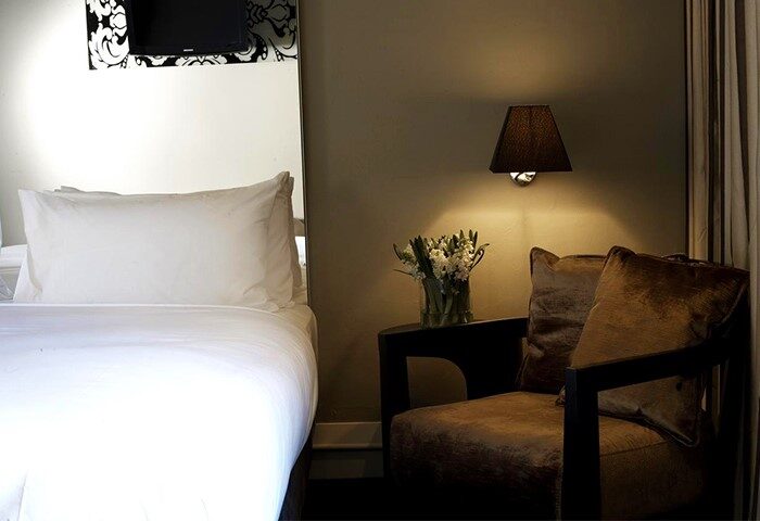 Kirketon Hotel Sydney room: Clean white bed, chair, flowers, and lamp. A big, cheap hotel in Sydney City Center for gay travelers.