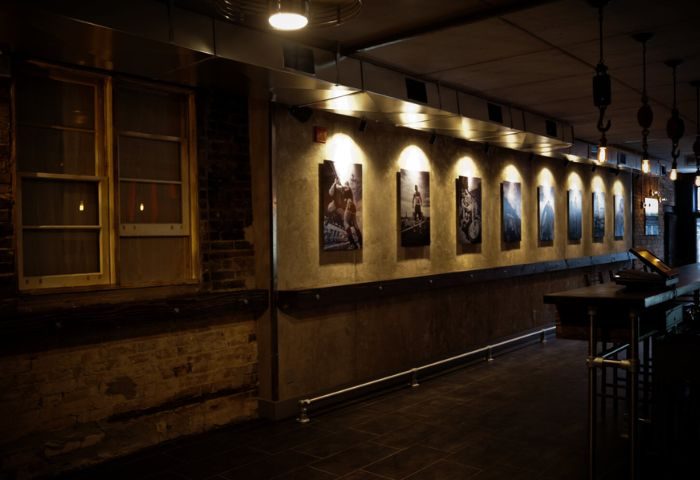 Interior of Black Eagle cruising bar in Toronto. Exposed brick, industrial lighting, and artwork line the walls. Gay travel advice.