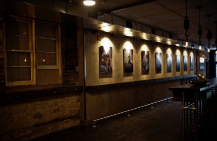 Interior of Black Eagle cruising bar in Toronto. Exposed brick, industrial lighting, and artwork line the walls. Gay travel advice.