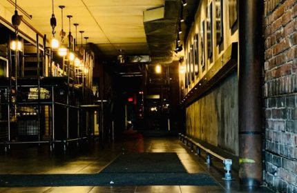 Interior of Black Eagle cruising bar in Toronto. Dim lighting, industrial design, bar stools, and exposed brick. Gay travel advice.