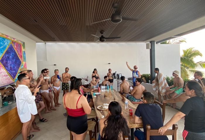 Gay party at Blondies Loft Slushbar in Puerto Vallarta. Men in swimwear gather around a table, enjoying drinks and socializing. Gay travel.