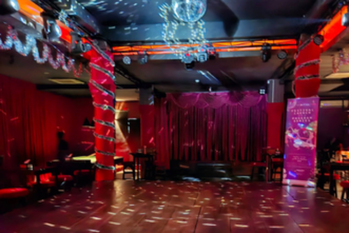 Blue Chilli gay bar in Phnom Penh. Stage with red curtains, disco ball, and red lighting. Gay travel advice for Phnom Penh nightlife.