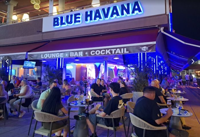 Blue Havana gay bar in Gran Canaria. Lounge bar with cocktails. People sit at tables outside. Nightlife scene. Gay travel.