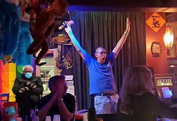 Bobby's Monkey Bar in Key West: A gay man sings karaoke with enthusiasm. Funny meme of Bernie Sanders in the background. Gay travel.